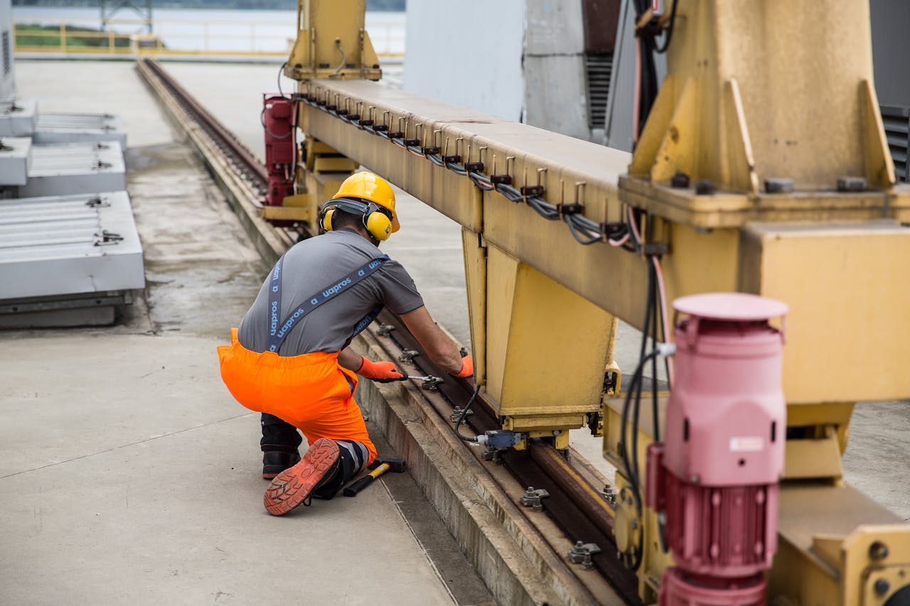 contact-img Worker in safety gear inspecting machinery on an outdoor industrial site.